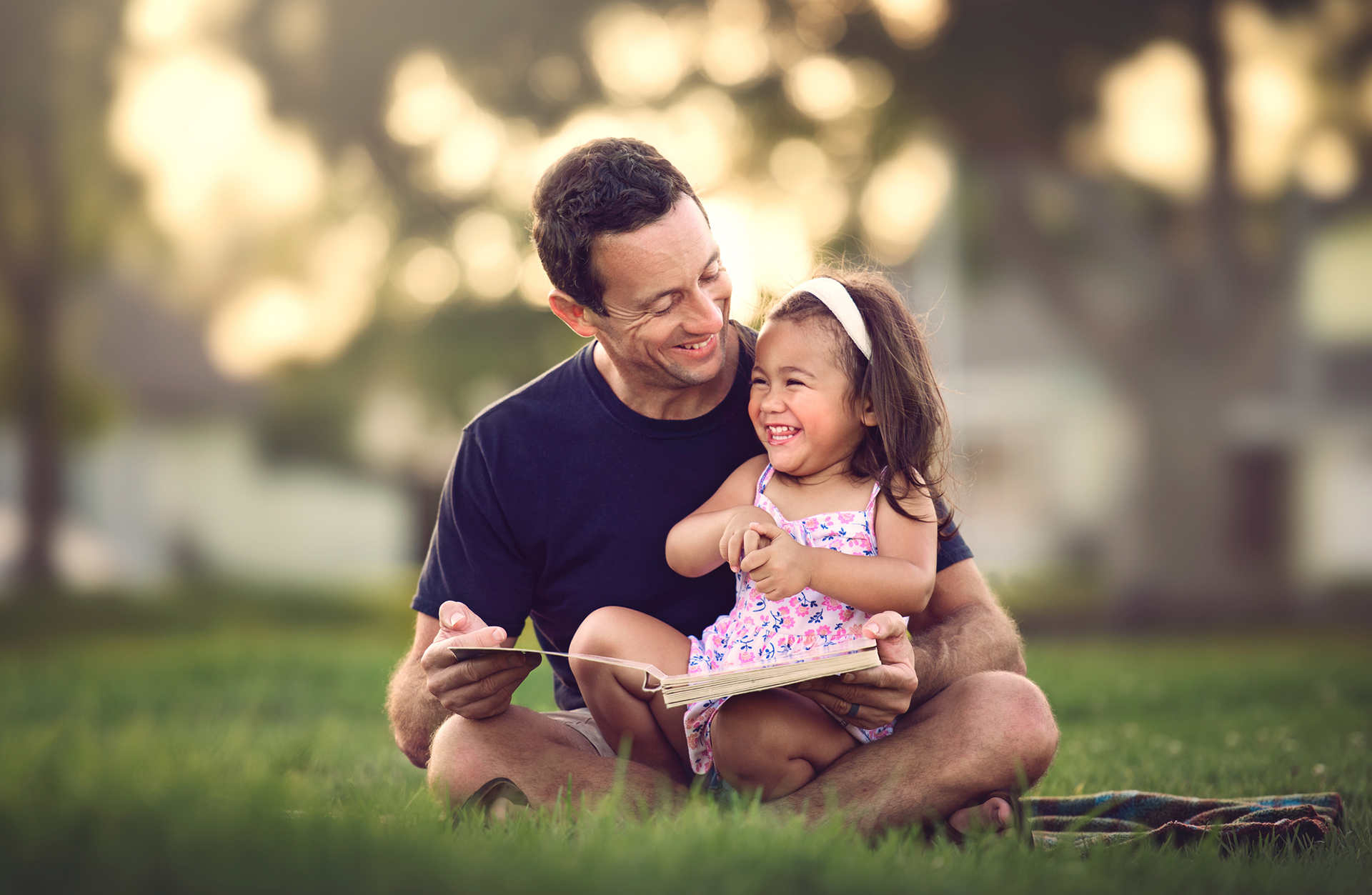Father and daughter reading together in a park